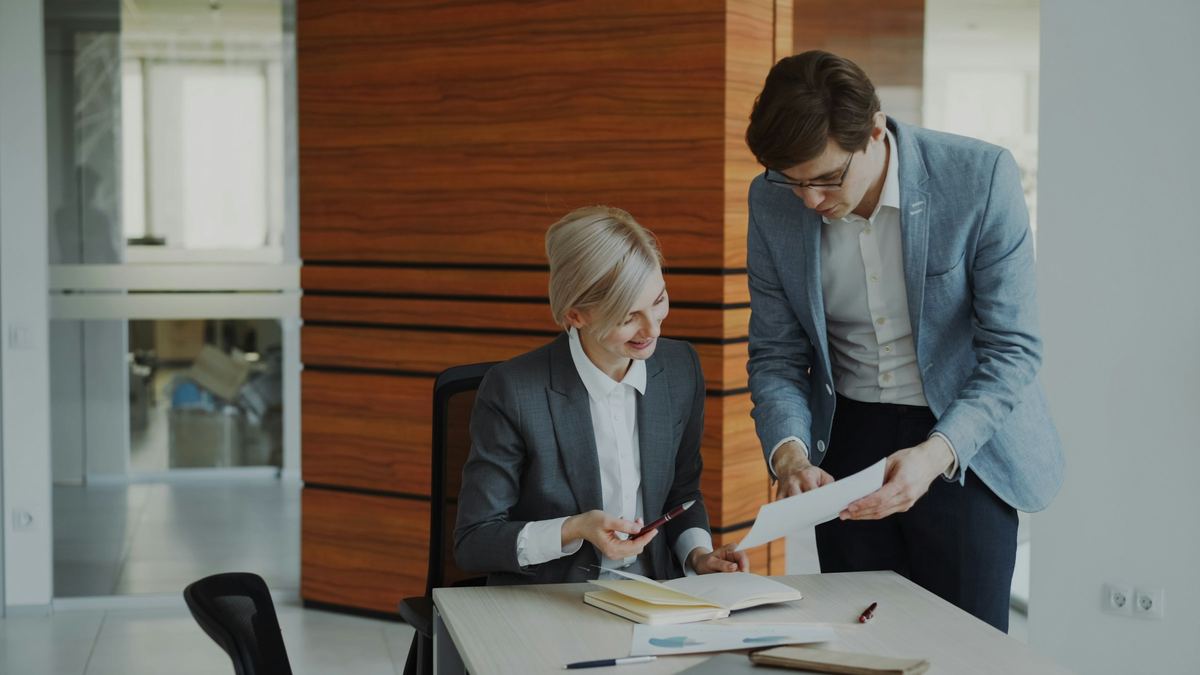 Two colleagues go over a report together at an office desk