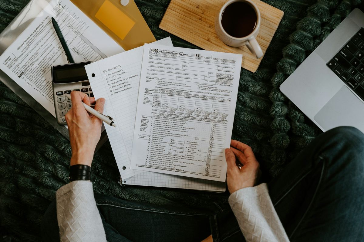 Hands working through printed financial documents with a calculator and a cup of coffee
